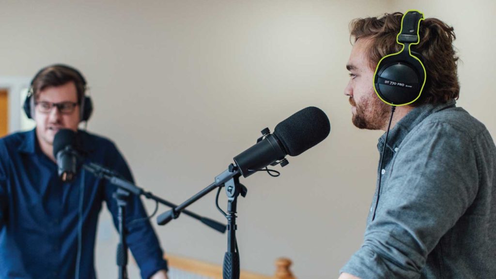 Two men recording a podcast with headphones highlighted in green