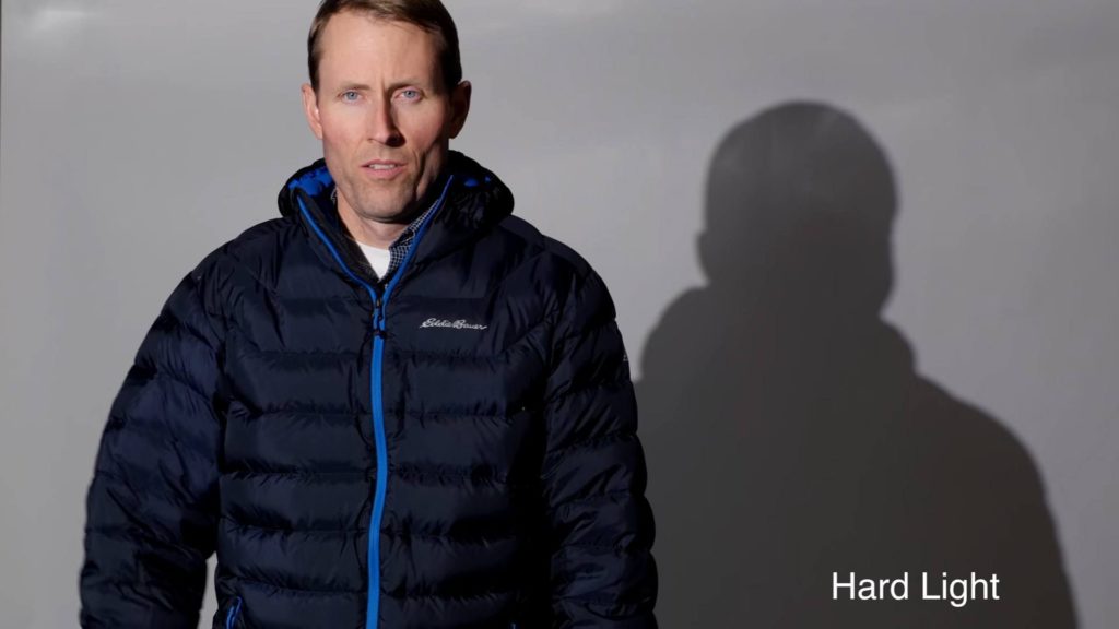 Man standing in front of gray background with a cold hard light on him