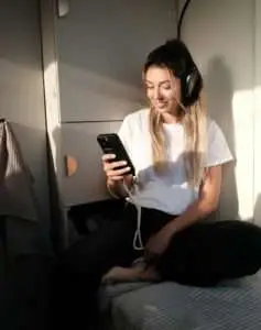 Podcast Marketing - Woman sitting with headphones looking at the phone